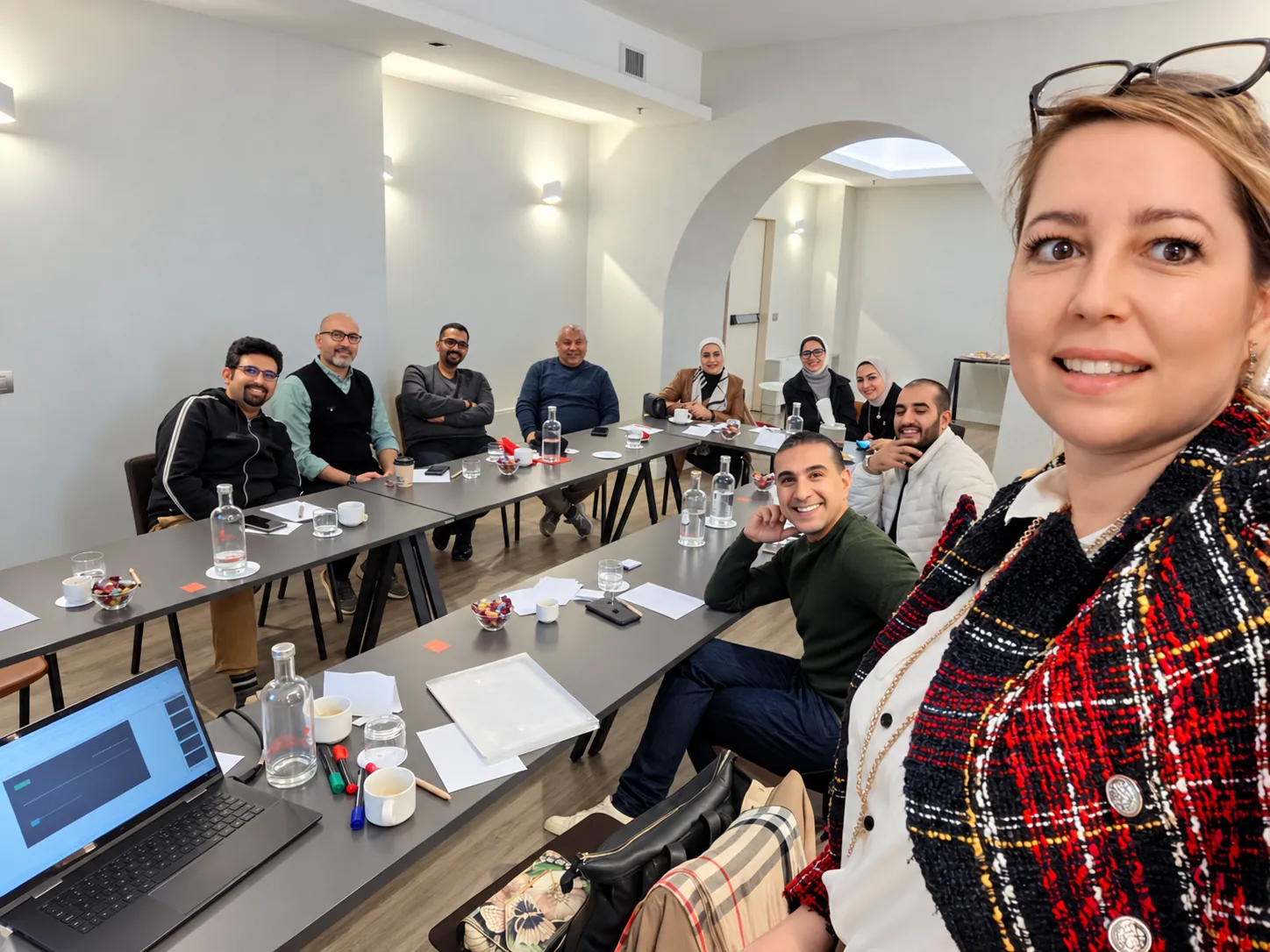 Trainer taking a group selfie with delegates around a long table